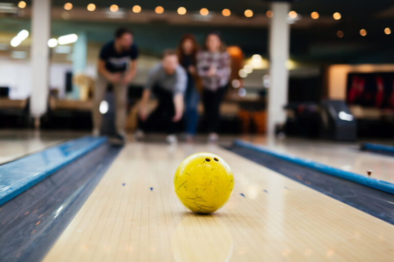 Gelber Bowlingball in der Bowlingbahn – Gruppe im Hintergrund beim Freizeit‑Ausflug im Haus Silberbach